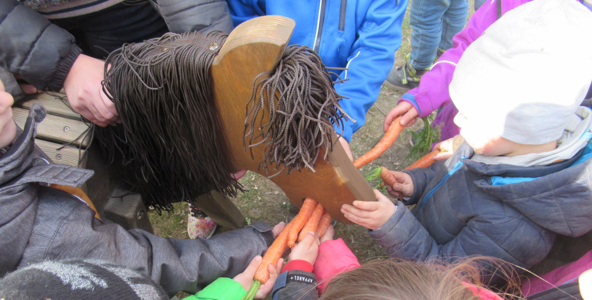 Kinder füttern Holzpferde mit Karotten